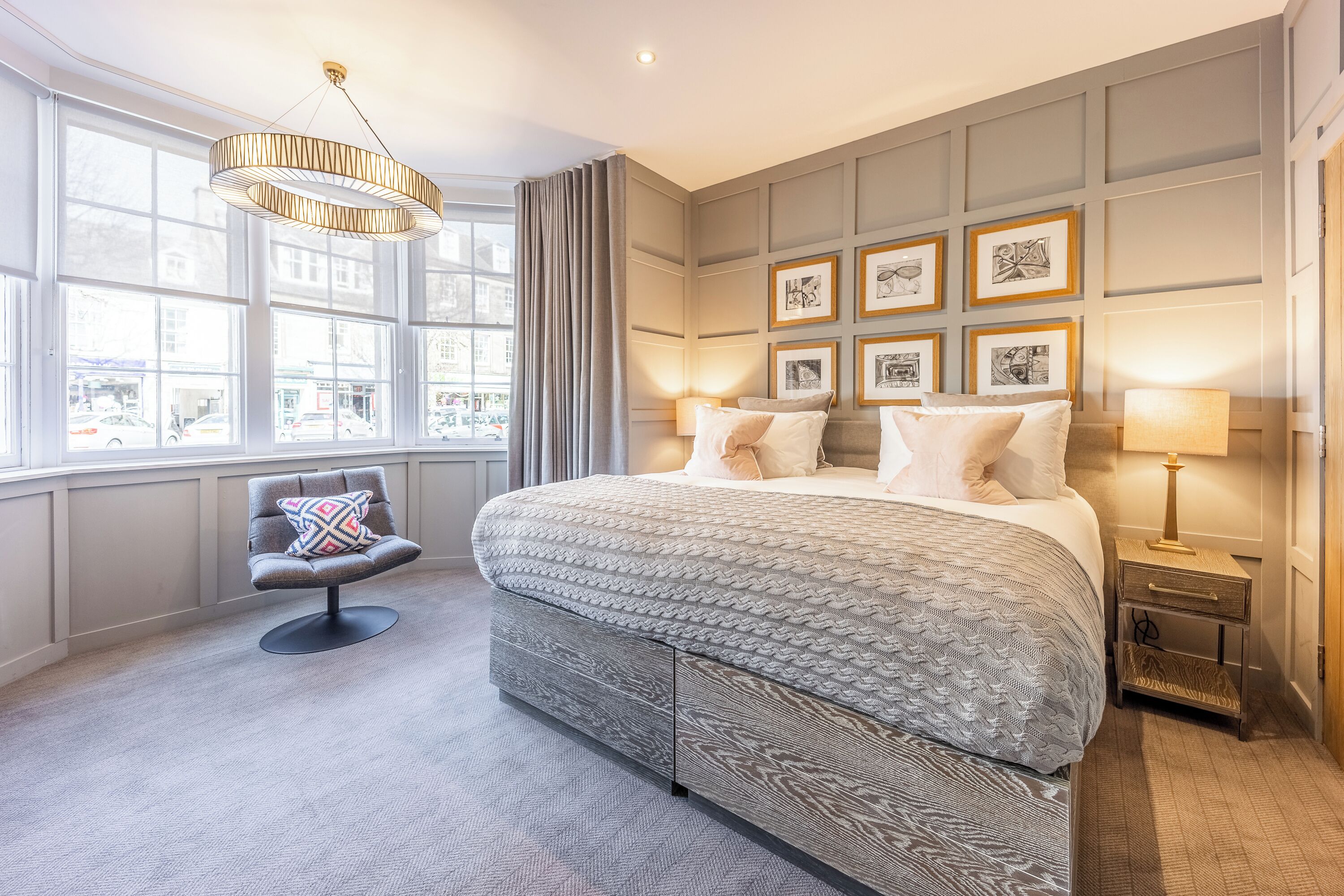 Een moderne slaapkamer met een groot bed, een nachtkastje, een stoel en uitzicht op de stad door grote ramen.