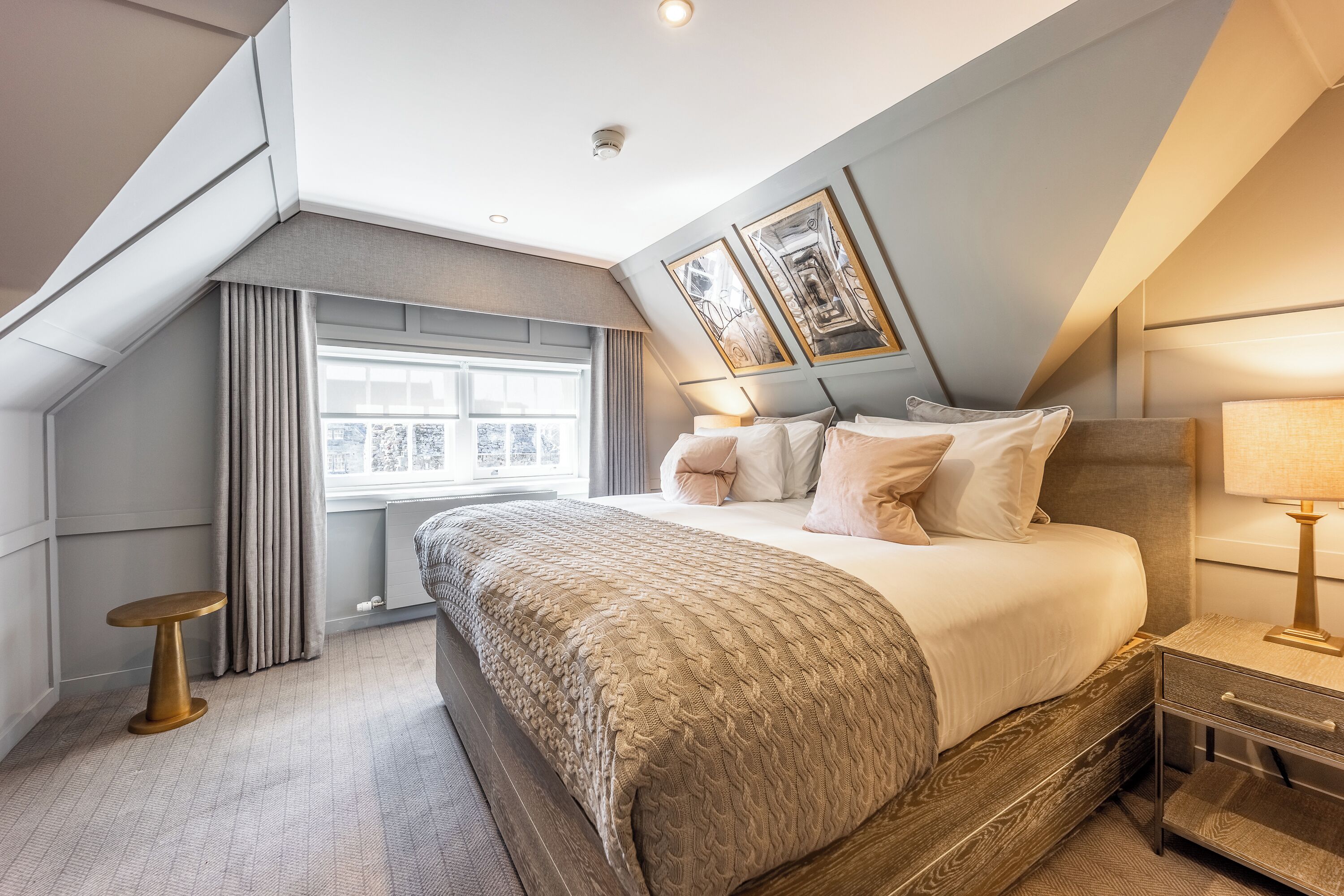 A modern bedroom with a large bed, a bedside table, a window with curtains, and a ceiling light.