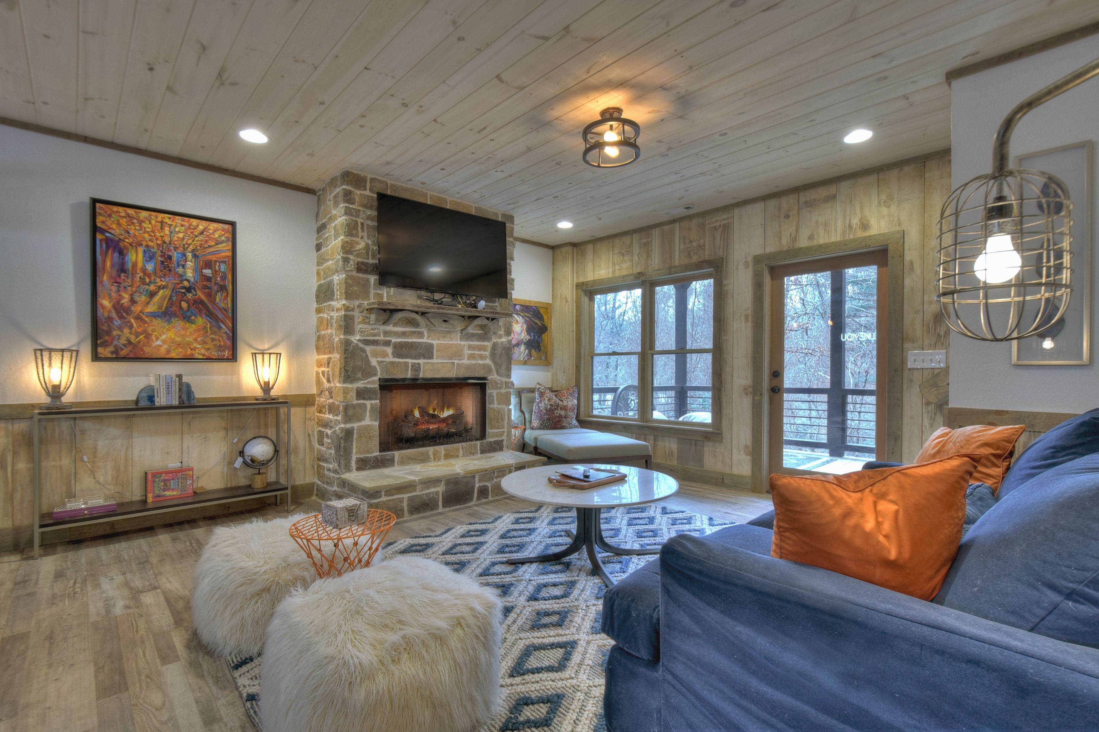 A cozy living room with a stone fireplace, a large painting, and a comfortable seating area.