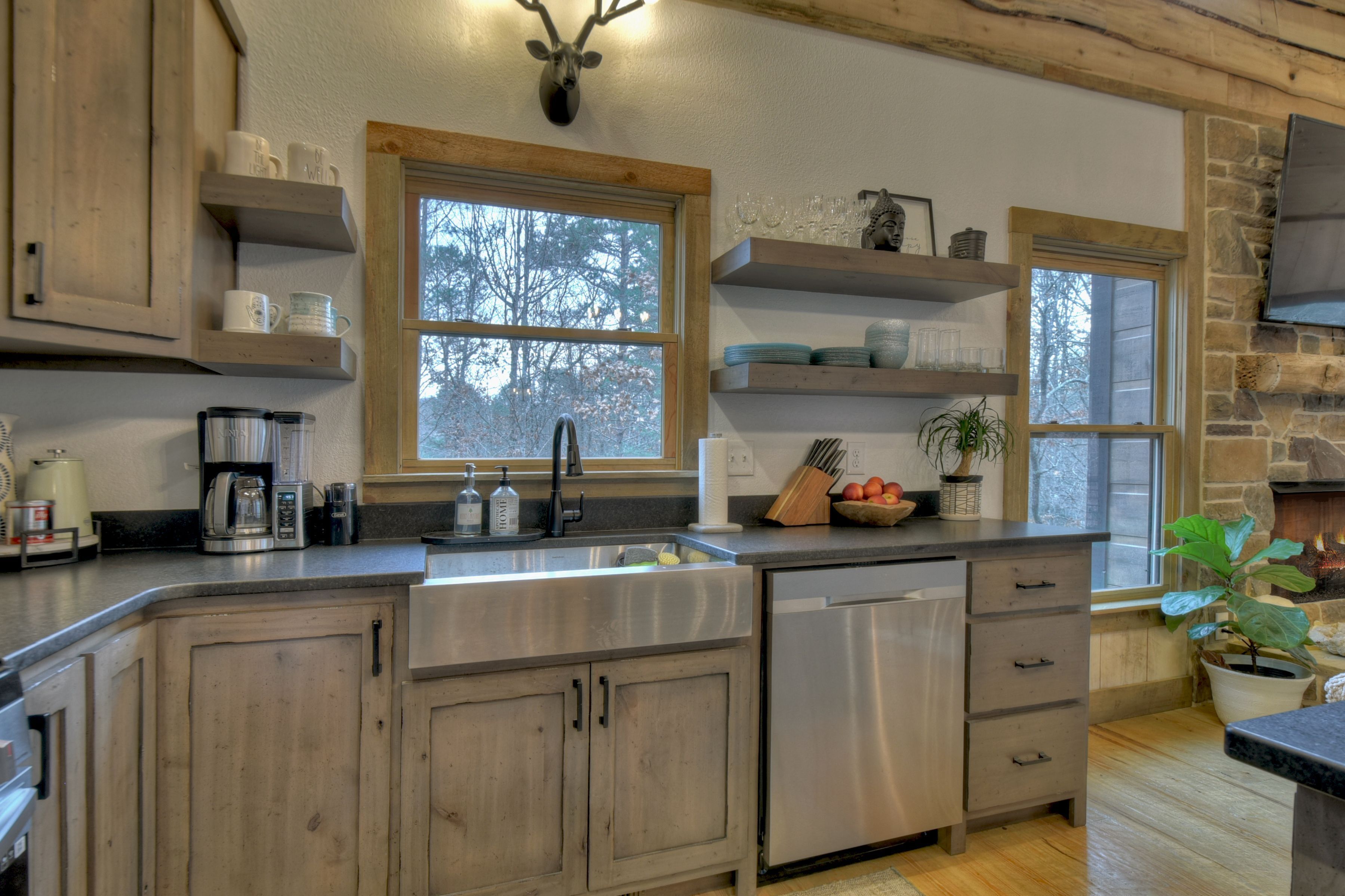 A kitchen with wooden cabinets, a stainless steel sink, and a stone wall.