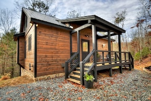 Une cabane en bois dotée d’un porche et d’un escalier menant à une terrasse.