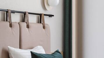 A neatly arranged bedroom with a bed, pillows, a headboard, and a wall-mounted light fixture.