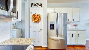 Una cocina moderna con armarios blancos, un refrigerador de acero inoxidable y un microondas sobre la encimera.