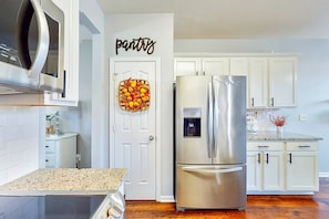 A modern kitchen with white cabinets, a stainless steel refrigerator, and a microwave above the counter.