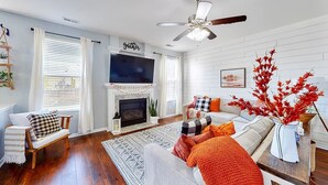 Una sala de estar con chimenea, ventilador de techo y televisor.