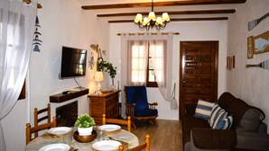 Ein gemütliches Wohnzimmer mit Essbereich, Holzmöbeln, einem Fernseher und einer Chandelier.