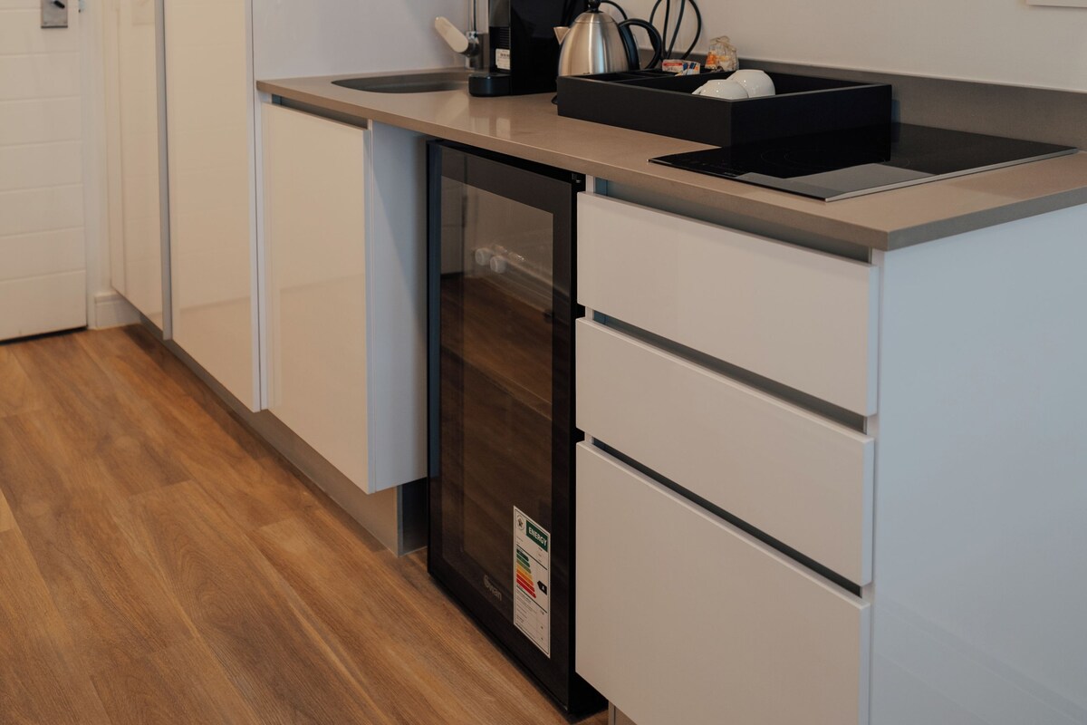 A modern kitchen with white cabinets, a stainless steel sink, and a built-in microwave.