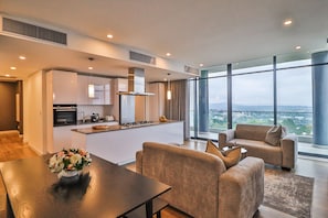 A modern apartment with a kitchen, dining area, and a living room with a large window offering a city view. - Reserved Suites Illovo (Sandton)