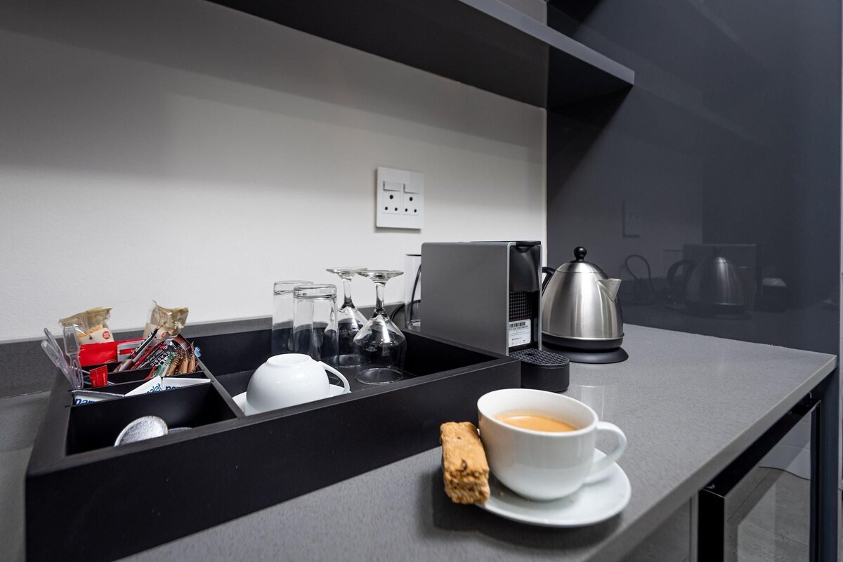 Una cocina moderna con cafetera, tetera y cristalería.