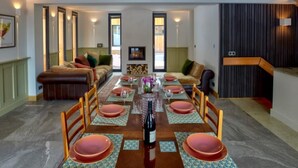 A dining area with a long table set for six, flanked by sofas and a fireplace. - Chalet nestled above the slopes at Les Houches (Les Houches)