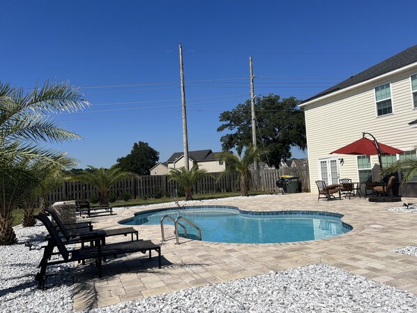 A backyard with a swimming pool, patio furniture, and a wooden fence. - A family home that is perfect for any trip to beautiful Savannah! (Savannah)