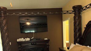 Una camera da letto con un letto grande, una TV a schermo piatto montata a parete, un comò in legno e uno specchio.