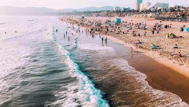 A crowded beach with people and tents, a lifeguard tower, and buildings in the background. - Beautiful 2 Bedroom Home in Santa Monica (Santa Monica)