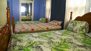 A bedroom with two single beds, a wooden headboard, a mirror, and a window with curtains.