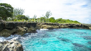 A coastal scene with clear turquoise waters, rocky cliffs, and lush greenery. - Maranatha Villa (Discovery Bay)