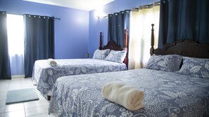A bedroom with two beds, blue walls, and curtains. - Maranatha Villa (Discovery Bay)