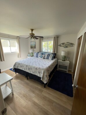 Restful retreat with a large bed and star-patterned bedspread, ceiling fan, and bedside table with lamp.