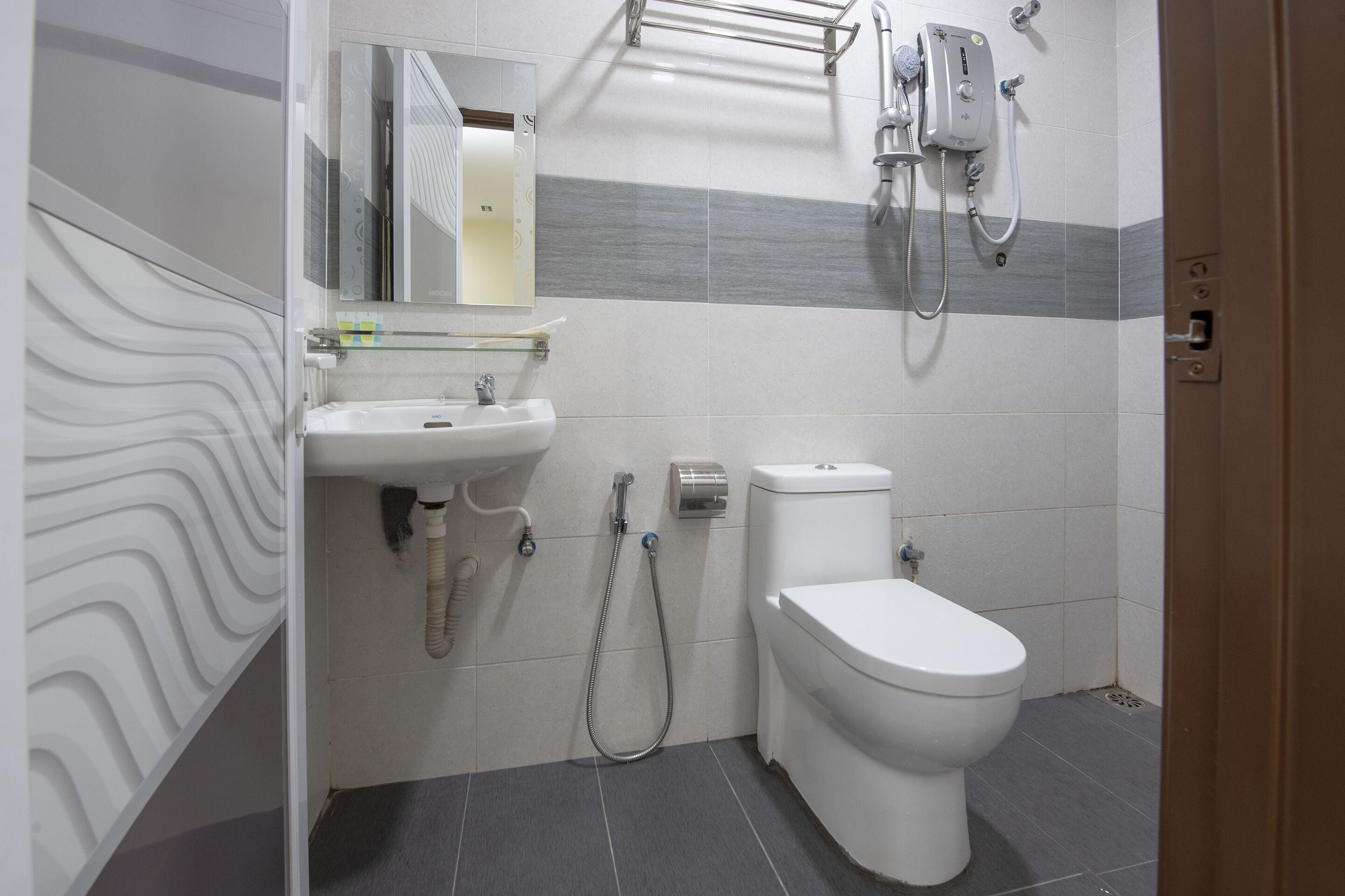A modern bathroom with a white sink, a toilet, and a shower unit.