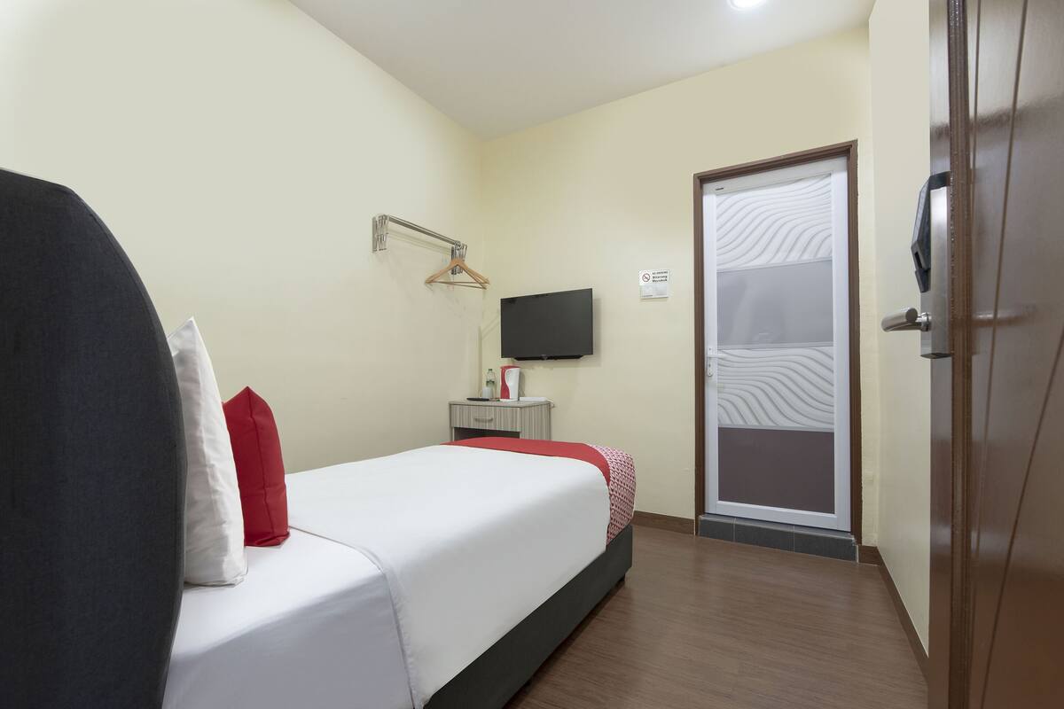 Ein Hotelzimmer mit Bett, Fernseher, Kleiderschrank und einer Tür mit Milchglasfenster.