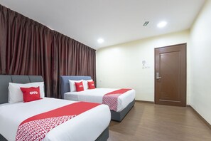 Habitación de hotel con dos camas, cada una con ropa blanca y detalles rojos, un ventanal con cortinas y una puerta de madera.