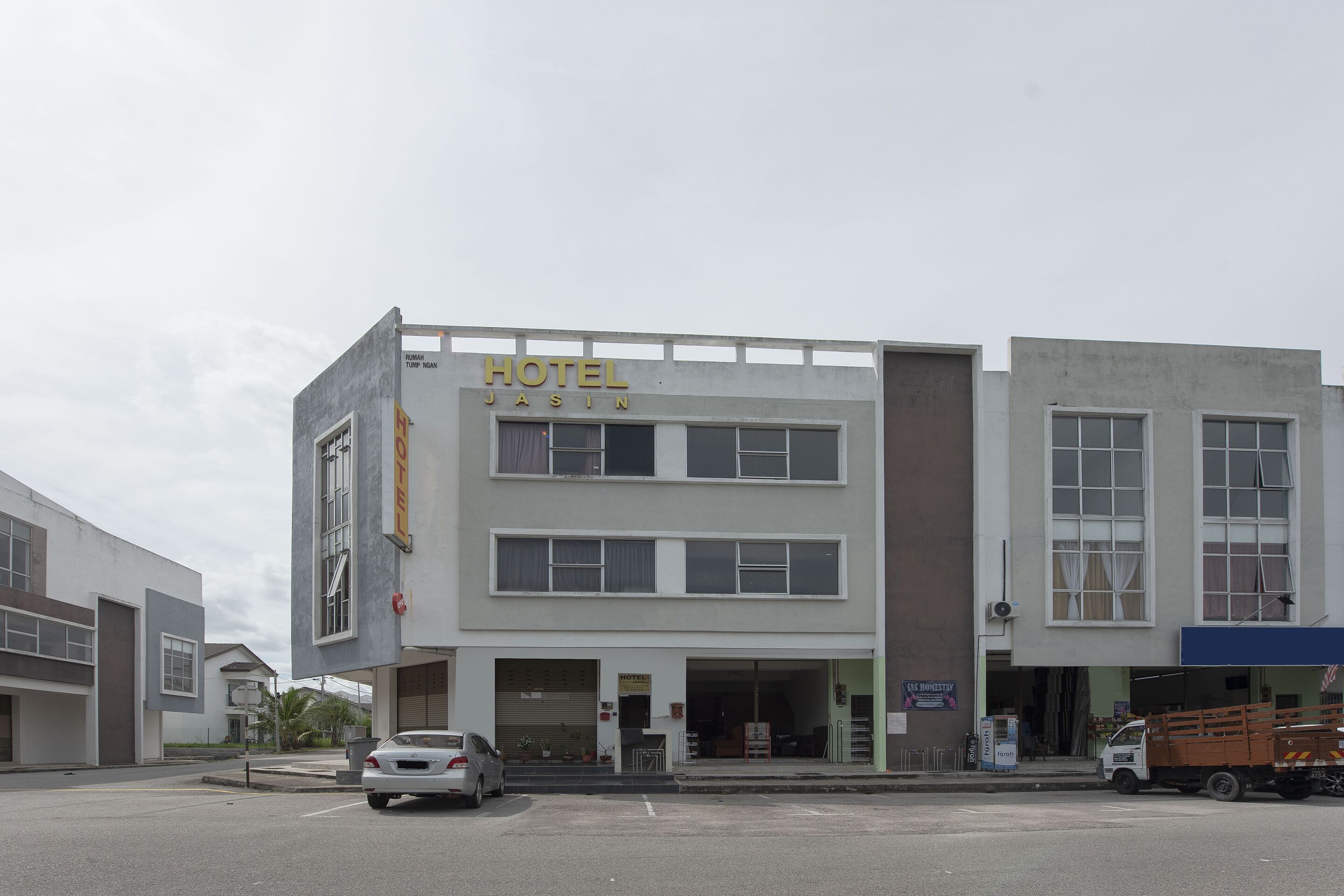 Een gebouw met twee verdiepingen waarop een bord staat met de tekst 'HOTEL JASIN'.