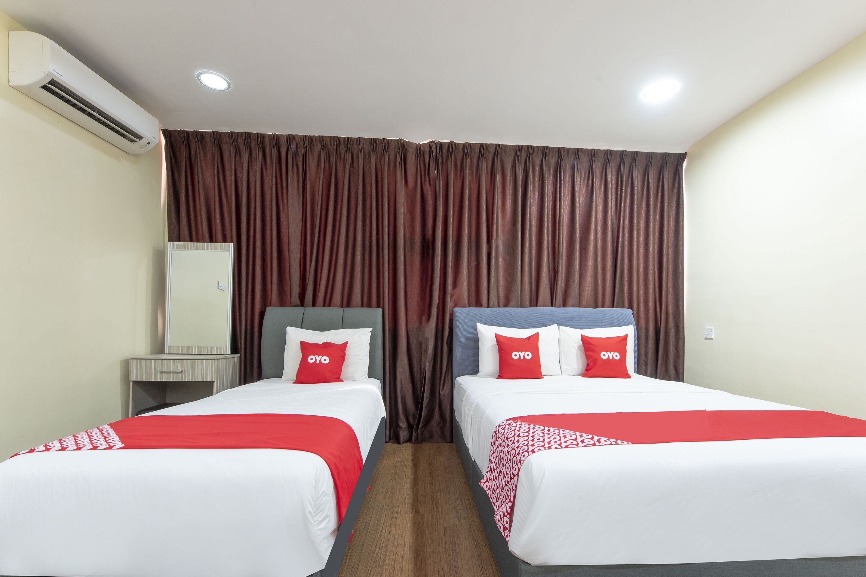 Habitación de hotel con dos camas, un espejo y un equipo de aire acondicionado.