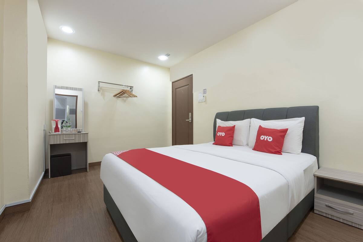 Ein Hotelzimmer mit einem Bett, einem Nachttisch, einem Spiegel, einem Kleiderschrank und einer Tür.
