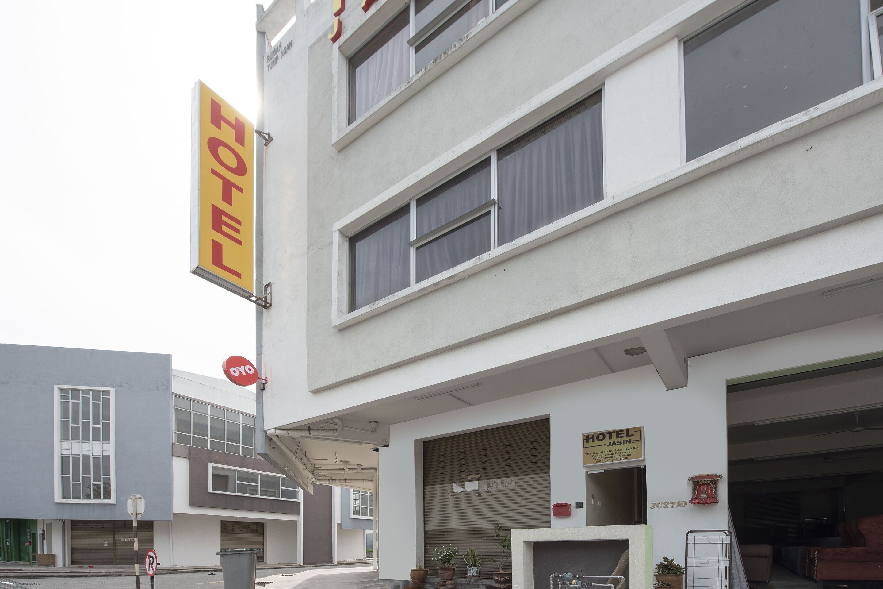 Un hotel con un llamativo letrero amarillo, múltiples ventanas y acceso a un garaje.