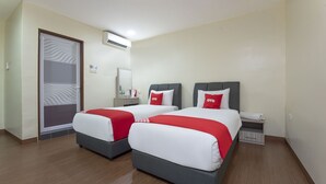 Ein Hotelzimmer mit zwei Betten, jeweils mit roter und weißer Bettwäsche, einem kleinen Nachttisch, einem Spiegel und einem Kleiderschrank.