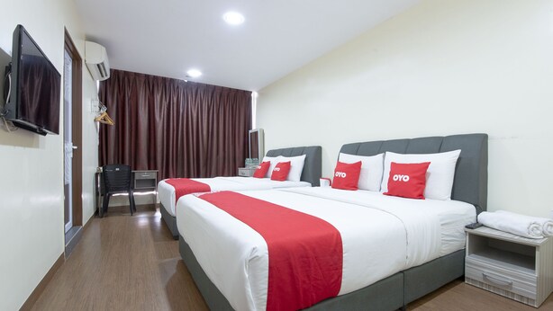 Ein Hotelzimmer mit zwei Betten, einem Fernseher, einer Klimaanlage, einem Schreibtisch und einem Stuhl.