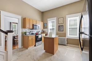 A modern kitchen with wooden cabinets, stainless steel appliances, and a marble countertop.