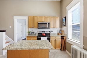 A kitchen with wooden cabinets, a microwave, a toaster, and a stove.