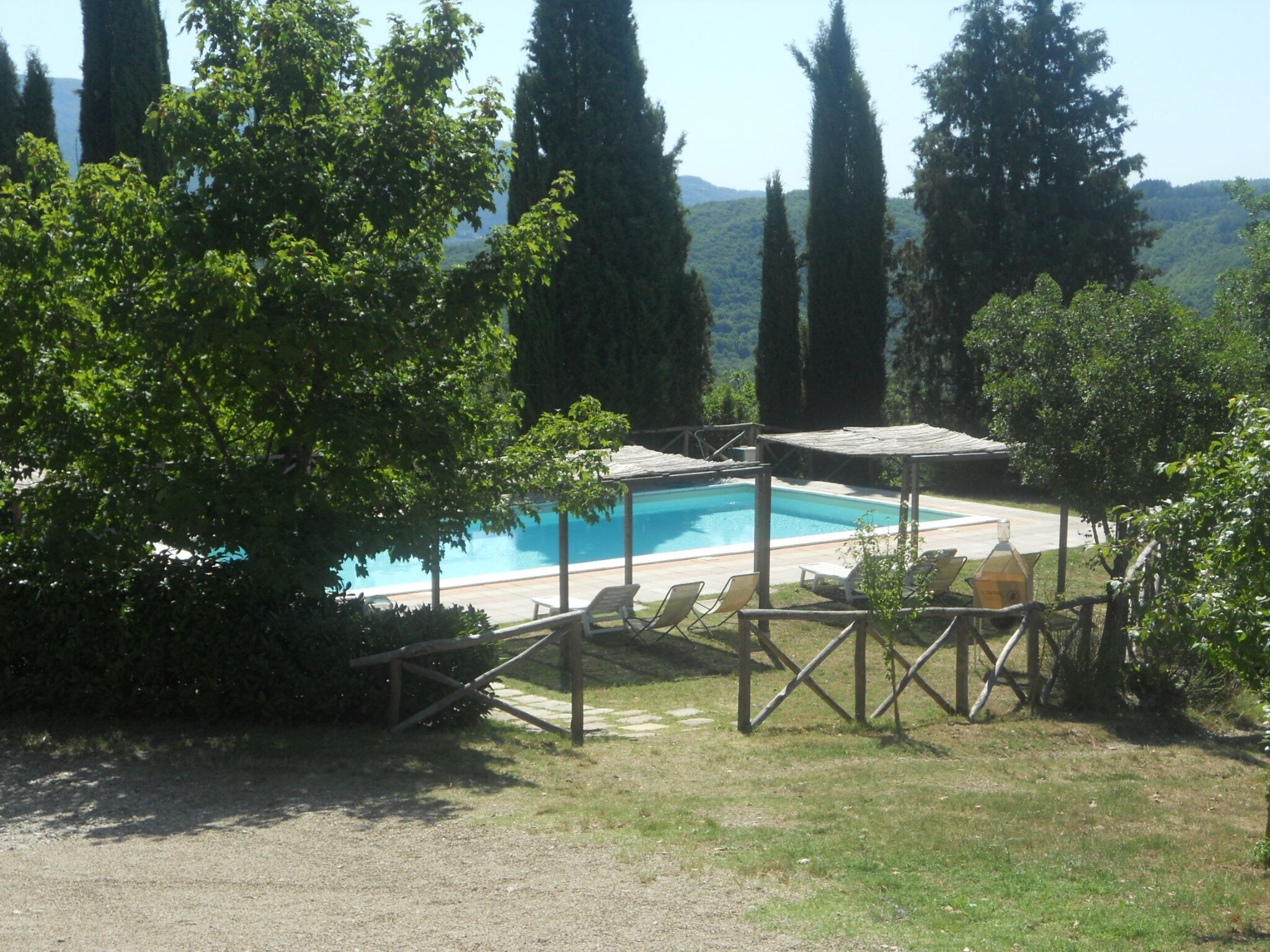 Zona de piscina con vista despejada, rodeada de árboles y una valla de madera.