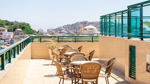Una terraza en la azotea con mobiliario de mimbre y vistas a un paisaje urbano.