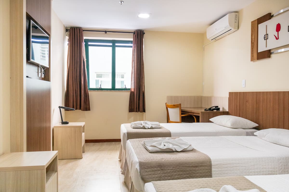 Habitación de hotel con dos camas, un escritorio, una silla, un televisor y un equipo de aire acondicionado.