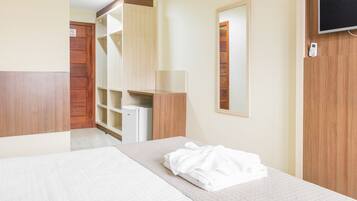 Una habitación de hotel con cama, armario, espejo y televisor.