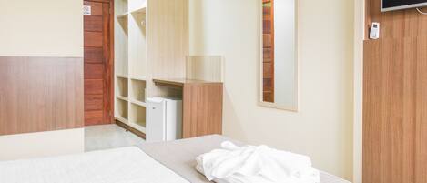 A hotel room with a bed, a wardrobe, a mirror, and a television.