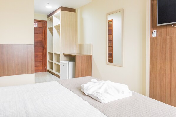 Une chambre d’hôtel comprenant un lit, une armoire, un miroir et un téléviseur.