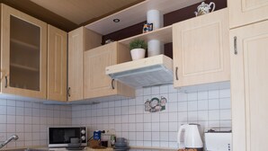 Une cuisine avec des meubles de rangement en bois, un four à micro-ondes, une cuisinière et un évier.