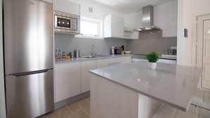 A modern kitchen with stainless steel appliances, a central island, and a window above the sink. - Newly renovated penthouse in a complex with pool on the seafront (Costa Teguise)