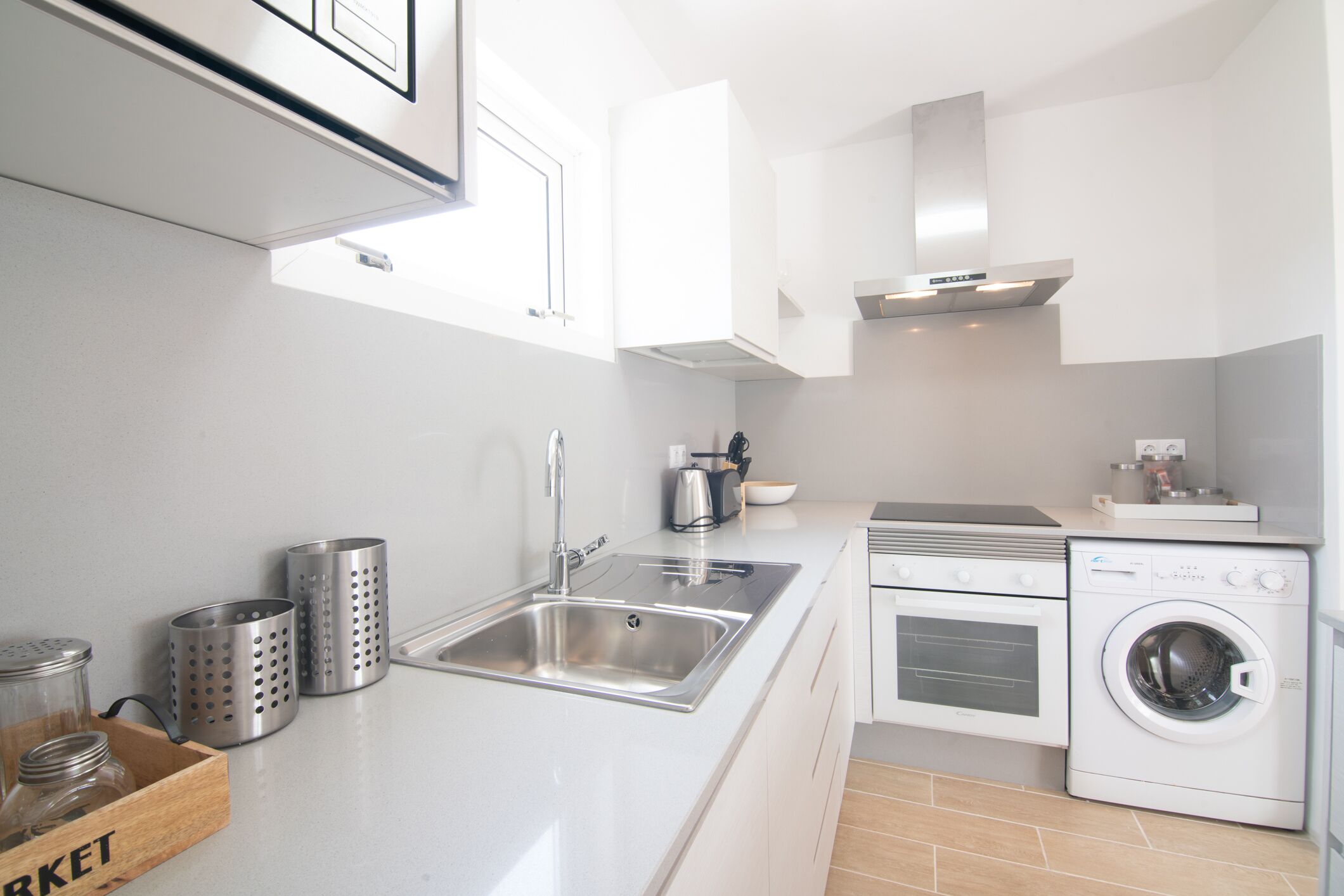 A modern kitchen with a stainless steel sink, a built-in oven, and a front-loading washing machine.