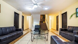 A lobby with two black leather sofas, a glass coffee table, a ceiling fan, and a staircase in the background. - OYO Hotel Bugambilia San Luis Potosi (San Luis Potosi)