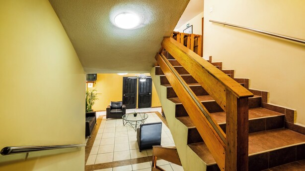 A staircase with wooden railings leading to a living area with a sofa, coffee table, and a potted plant. - OYO Hotel Bugambilia San Luis Potosi (San Luis Potosi)