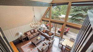 A spacious living area with a large sectional sofa, a coffee table, and a chandelier. - The Legacy Cabin | Hot Tub | Huge Fenced Yard (Windermere)