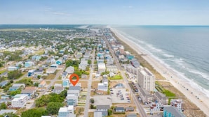 Une ville côtière dotée d’une plage, de bâtiments résidentiels et d’un hôtel imposant, reconnaissable à son grand bâtiment et à son drapeau.