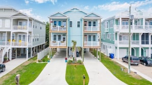 Une rangée de copropriétés de trois étages, situées en bord de mer, dotées de balcons, d’une allée centrale et d’une pelouse devant.