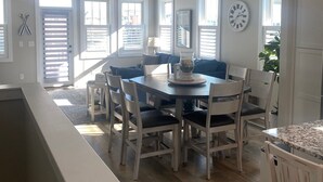 Un vaste espace dédié à la salle à manger, avec une table ronde, des chaises blanches et un ventilateur de plafond.