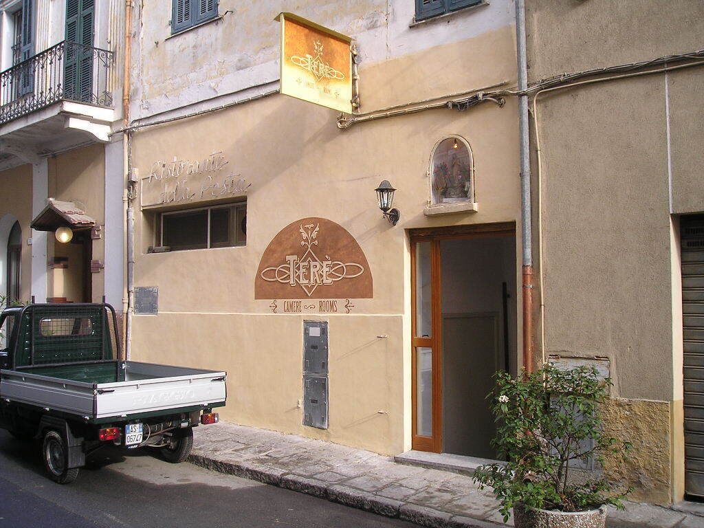 Ein Gebäude mit einem Schild, auf dem „Ristorante dell’Isola“ und „CAMERE & ROOMS“ steht, das anbietet sowohl Speisen als auch Übernachtung.