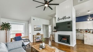 A spacious living room with a fireplace, a dining area, and a kitchen in the background. - OCEAN VIEWS! Steps away from the sand! (Galveston)