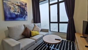 A modern living room with a sofa, a round coffee table, a painting, and a large window with curtains. - OYO Home 90400 One Tebrau Homestay (Johor Bahru)